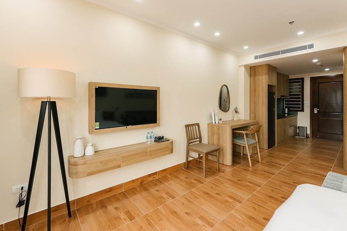 Une chambre d’hôtel comprenant un lit, un bureau avec une chaise, un téléviseur fixé au mur et une table de chevet avec une lampe.