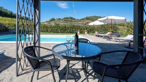 Un espace extérieur abrité comprenant une piscine, des chaises longues et une table avec des chaises.