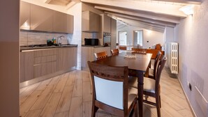 Une cuisine moderne avec des meubles en bois, un coin repas doté d’une grande table et de chaises, et un îlot de cuisine bien visible.