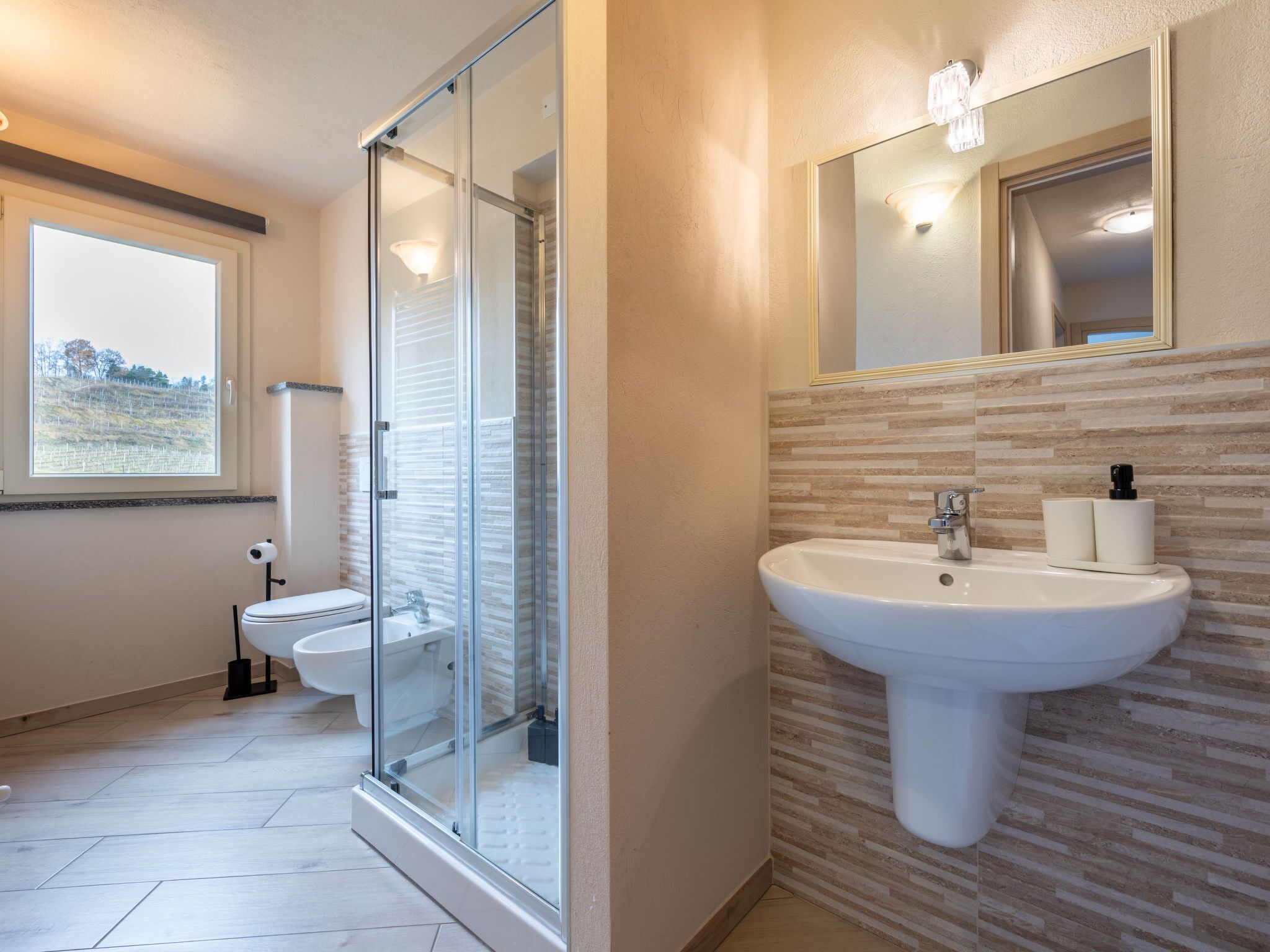 A modern bathroom with a glass-enclosed shower, a white sink, and a toilet.