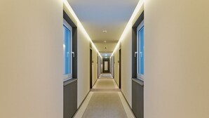 Ein moderner Hotelkorridor mit einem zentralen Teppichlaufsteg, beidseitig von Türen gesäumt.