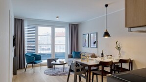 Ein modernes Wohnzimmer mit Essbereich, großen Fenstern und Blick auf Gebäude.