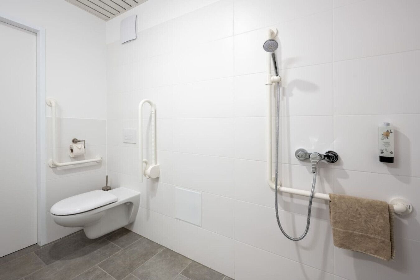 A modern bathroom with a toilet, a shower with a handheld showerhead, and a towel rack.