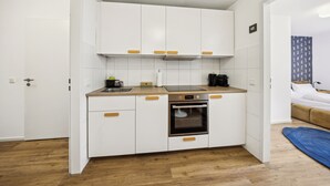 A compact kitchen with white cabinets, a built-in oven, and a wooden countertop. - Arbio I Cube Apartments (Hamburg)