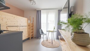Una cucina moderna con mobili in legno, un'area pranzo con un tavolino e due sedie, e una grande pianta in vaso.