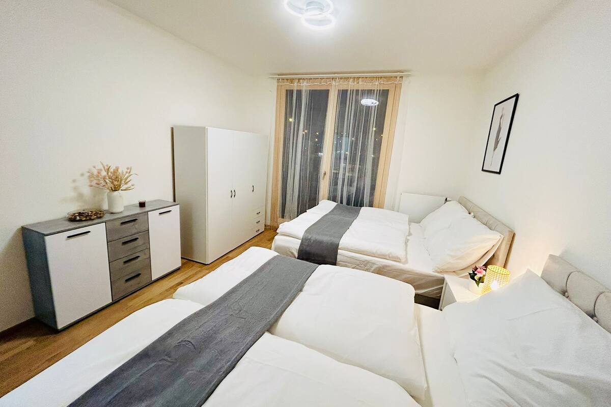 Een slaapkamer met twee bedden, een kledingkast, een bureau en een raam met gordijnen.