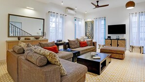 Un salon moderne comprenant un canapé, une table basse, un téléviseur à écran plat et un ventilateur de plafond.