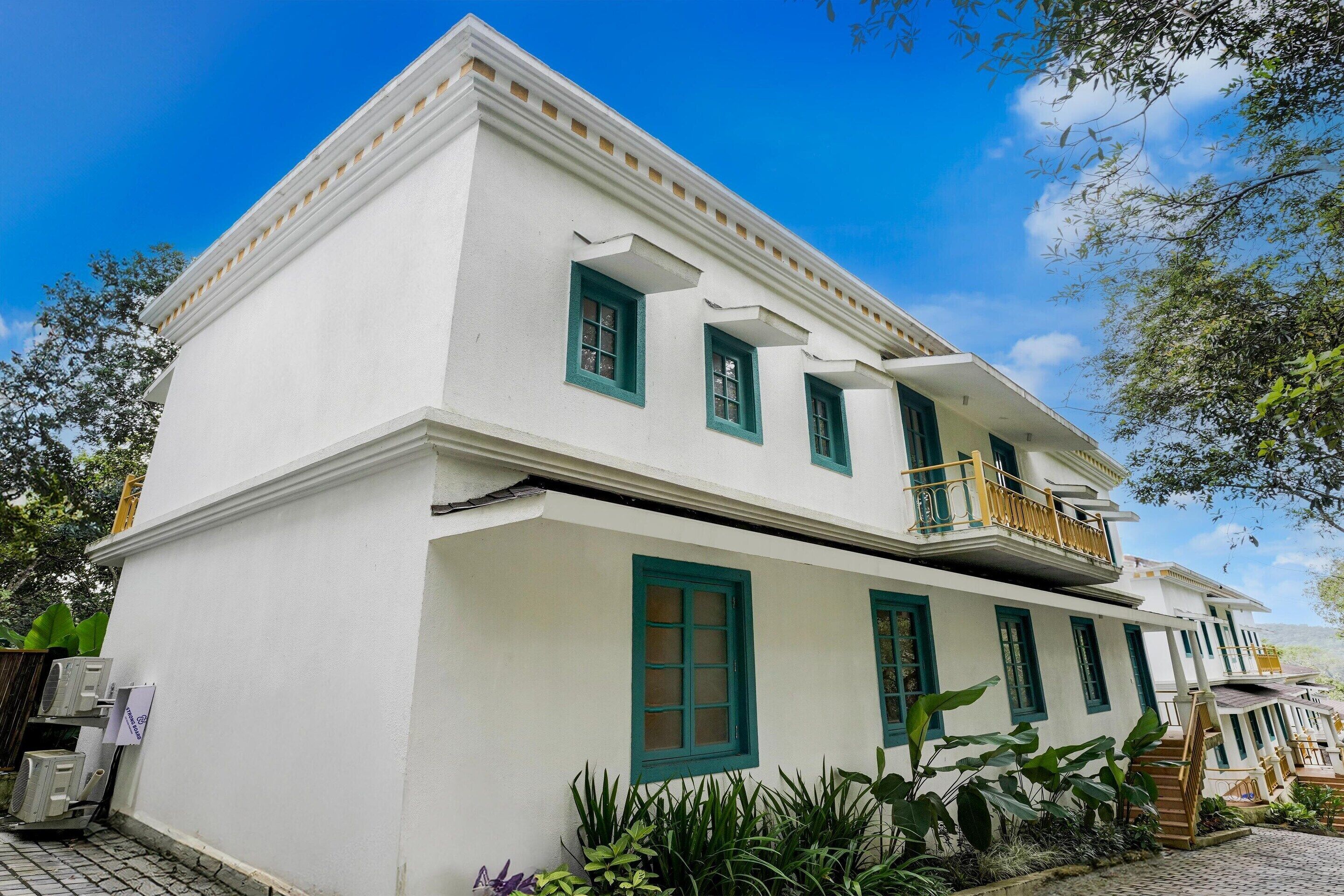 Un edificio blanco con ventanas verdes y un balcón.