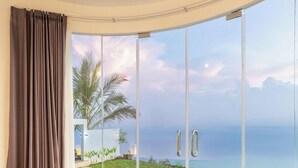 A bedroom with a large bed, a view of the ocean, and a sliding glass door. - Alam Nirwana Kintamani (Kintamani)