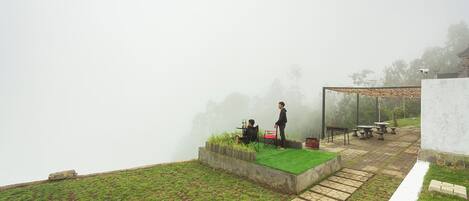 Un espacio exterior brumoso con una pequeña zona de estar y una estructura cubierta.