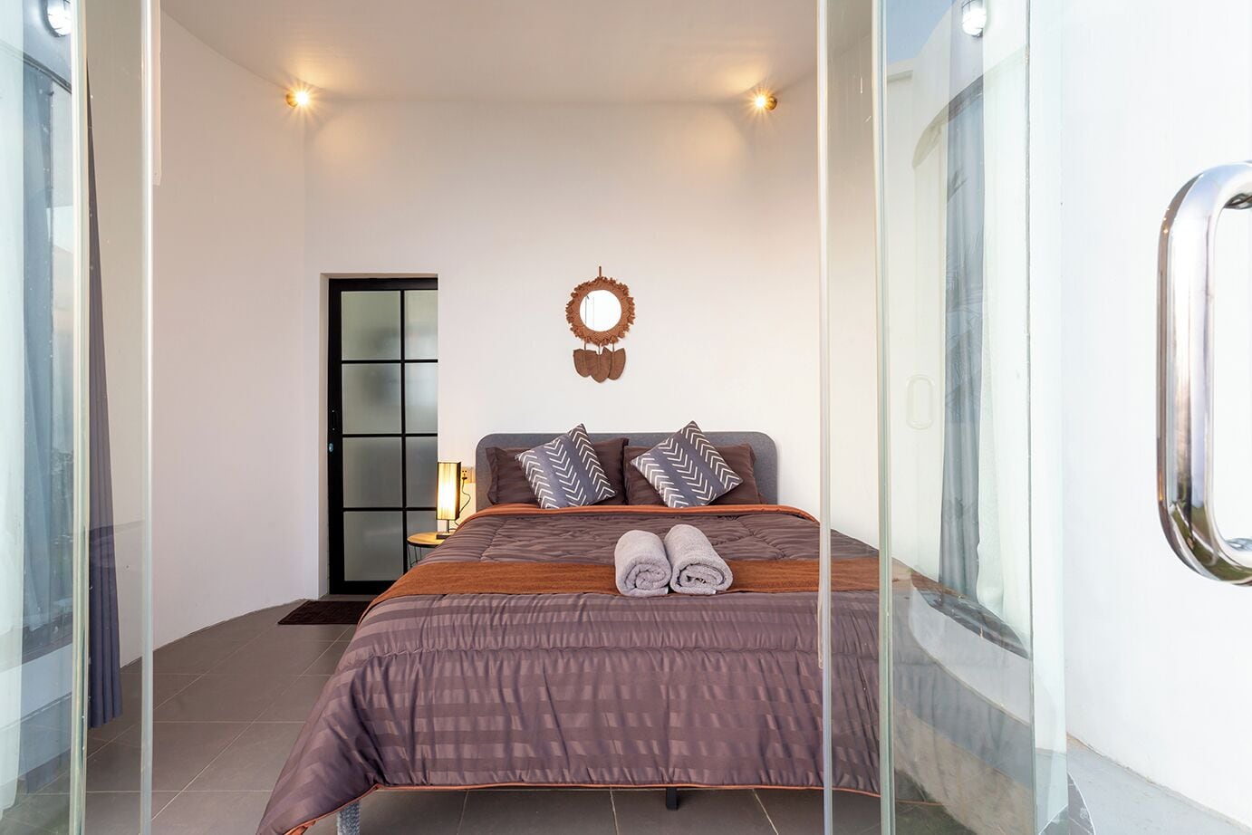 Un dormitorio moderno con una cama grande, un espejo y una puerta que da a otra habitación.