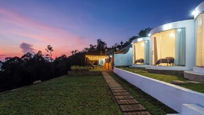 A modern house with a paved pathway leading to a covered outdoor area with string lights. - Alam Nirwana Kintamani (Kintamani)
