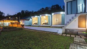 A modern house with three cylindrical rooms, a covered outdoor area with string lights, and a staircase leading to a second floor. - Alam Nirwana Kintamani (Kintamani)
