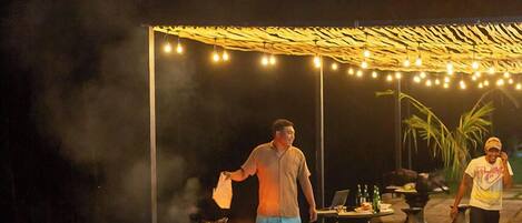 An outdoor patio area with a fire pit, tables, and string lights.