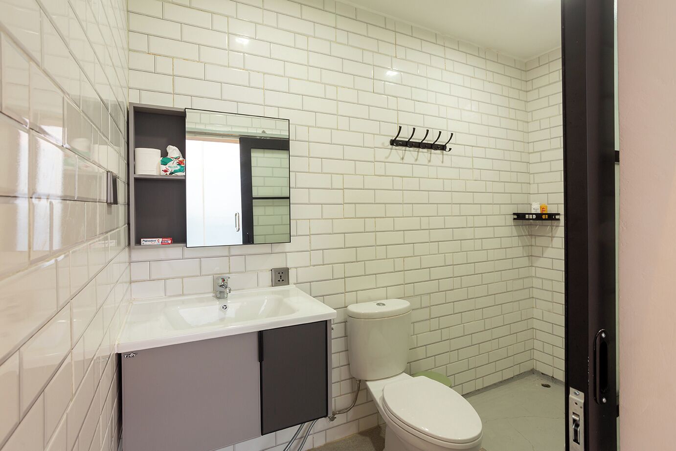 A modern bathroom with white subway tiles, a white sink, a toilet, and a mirror above the sink.