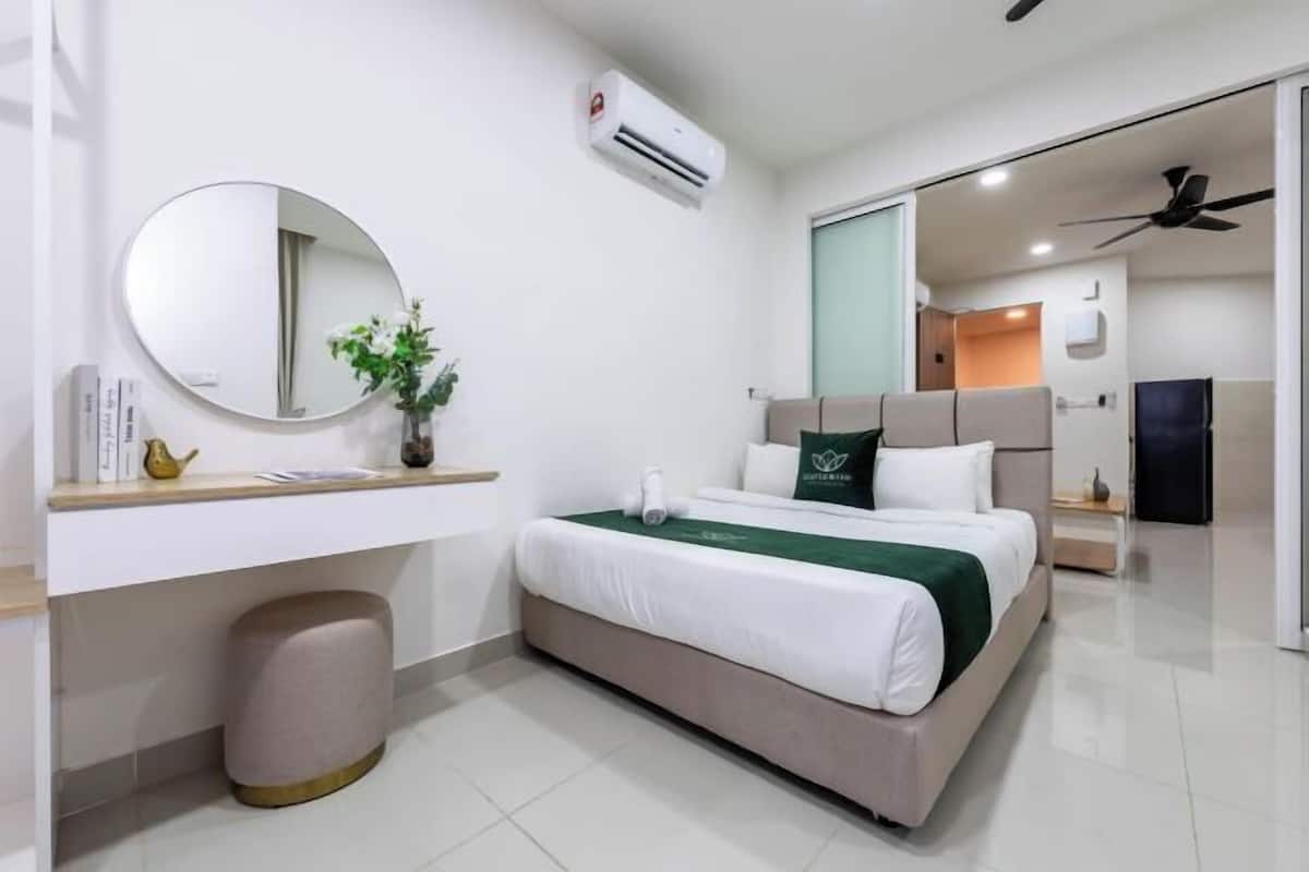 A modern hotel room with a bed, bedside table, mirror, and air conditioning unit.