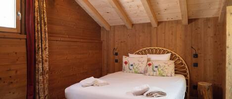Una stanza in legno con un letto, tende e una finestra.
