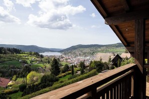 A wooden balcony overlooking a town with a lake and hills.