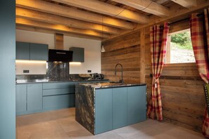 A modern kitchen with a central island, built-in appliances, and a window with curtains.