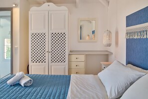 A bedroom with a bed, a wardrobe, a mirror, and a hanging light fixture. - Villa Lito Periyali (Zakynthos)