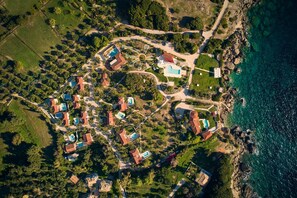 An aerial view of a coastal resort with multiple buildings, swimming pools, and a rocky shoreline. - Villa Lito Periyali (Zakynthos)