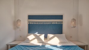 Ein Bett mit blauer Decke, weißen Kissen und zwei Hängeleuchten.