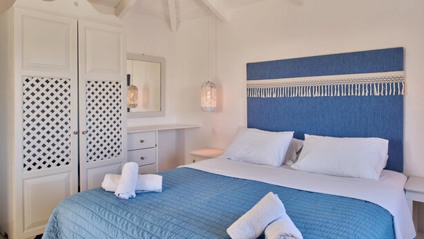 Ein Schlafzimmer mit einem Bett, einem weißen Kleiderschrank und einem blauen Kopfteil.