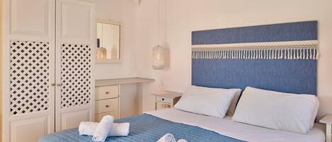 A neatly made bed with blue bedding and white pillows, a bedside table with a lamp, and a wardrobe with patterned doors.