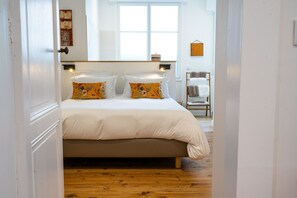 Un dormitorio con una cama grande, dos lámparas de noche y suelo de madera.