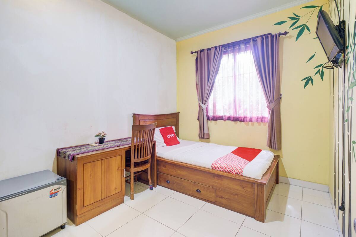 Une chambre à coucher comprenant un lit, un bureau, une chaise et un petit réfrigérateur.