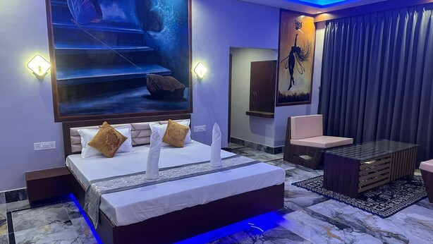 Une chambre moderne avec un grand lit, un coin salon et des œuvres d’art accrochées aux murs.