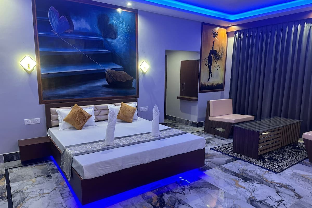A modern bedroom with a large bed, a seating area, and artwork on the walls.