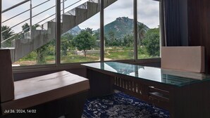 Une chambre moderne dotée d’une grande fenêtre donnant sur un paysage de montagne et de verdure.