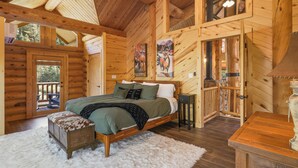 Un dormitorio tipo cabaña de madera con una cama de madera, un banco y una decoración rústica.