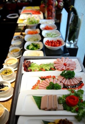 Un buffet con diverse portate, tra cui carni, verdure e salse.