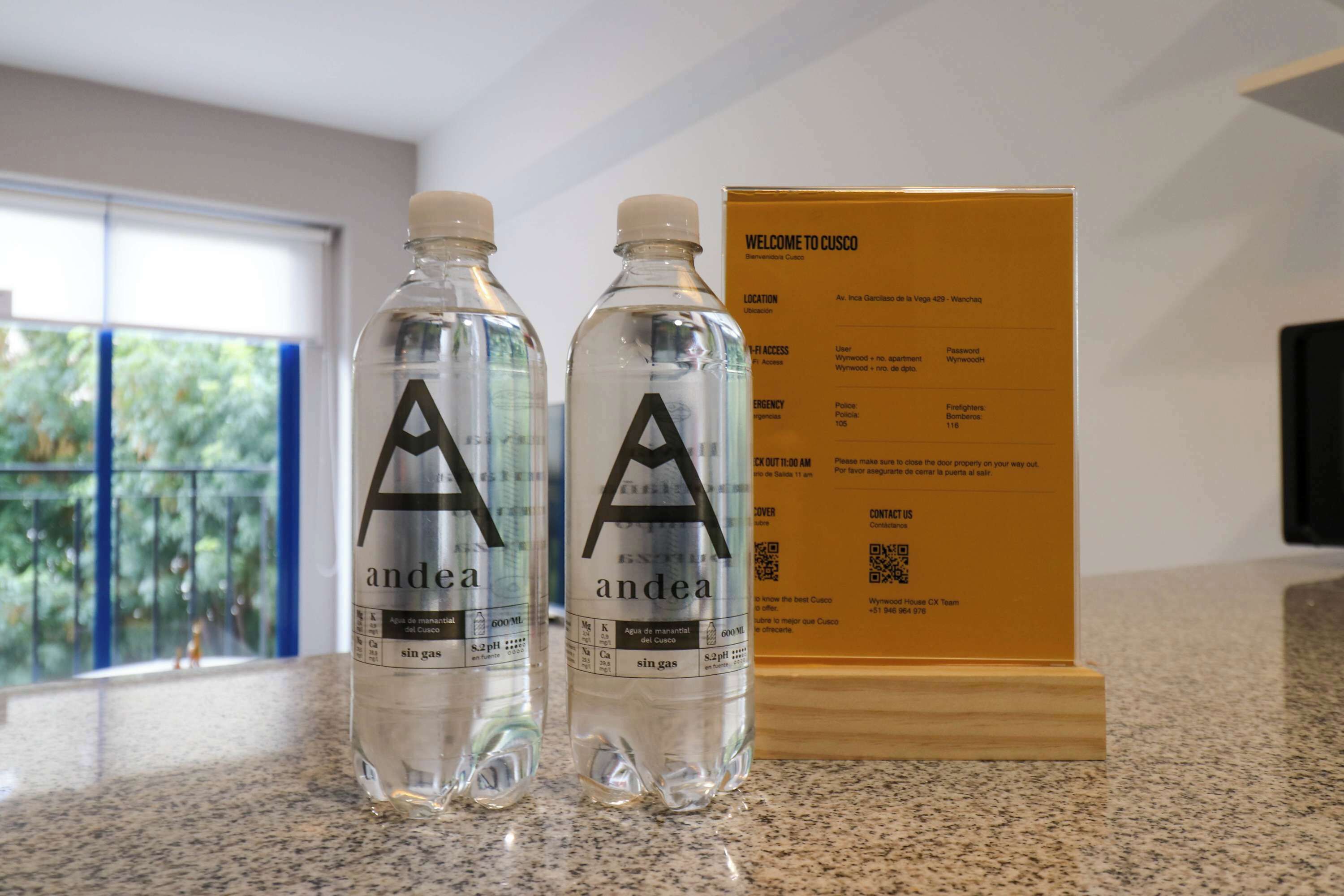 Two bottles of water labeled 'andea' on a countertop next to a welcome sign for Cusco.