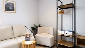 A modern living room with a beige sofa, a round wooden side table, a black metal shelving unit with towels and a plant. - w *|Grand 2BR w/ Lovely Terrace in Bocagrande (Cartagena de Indias)