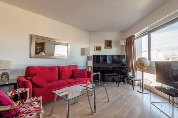 Ein modernes Wohnzimmer mit einem roten Sofa, einem Glastisch und einem Flachbildfernseher.