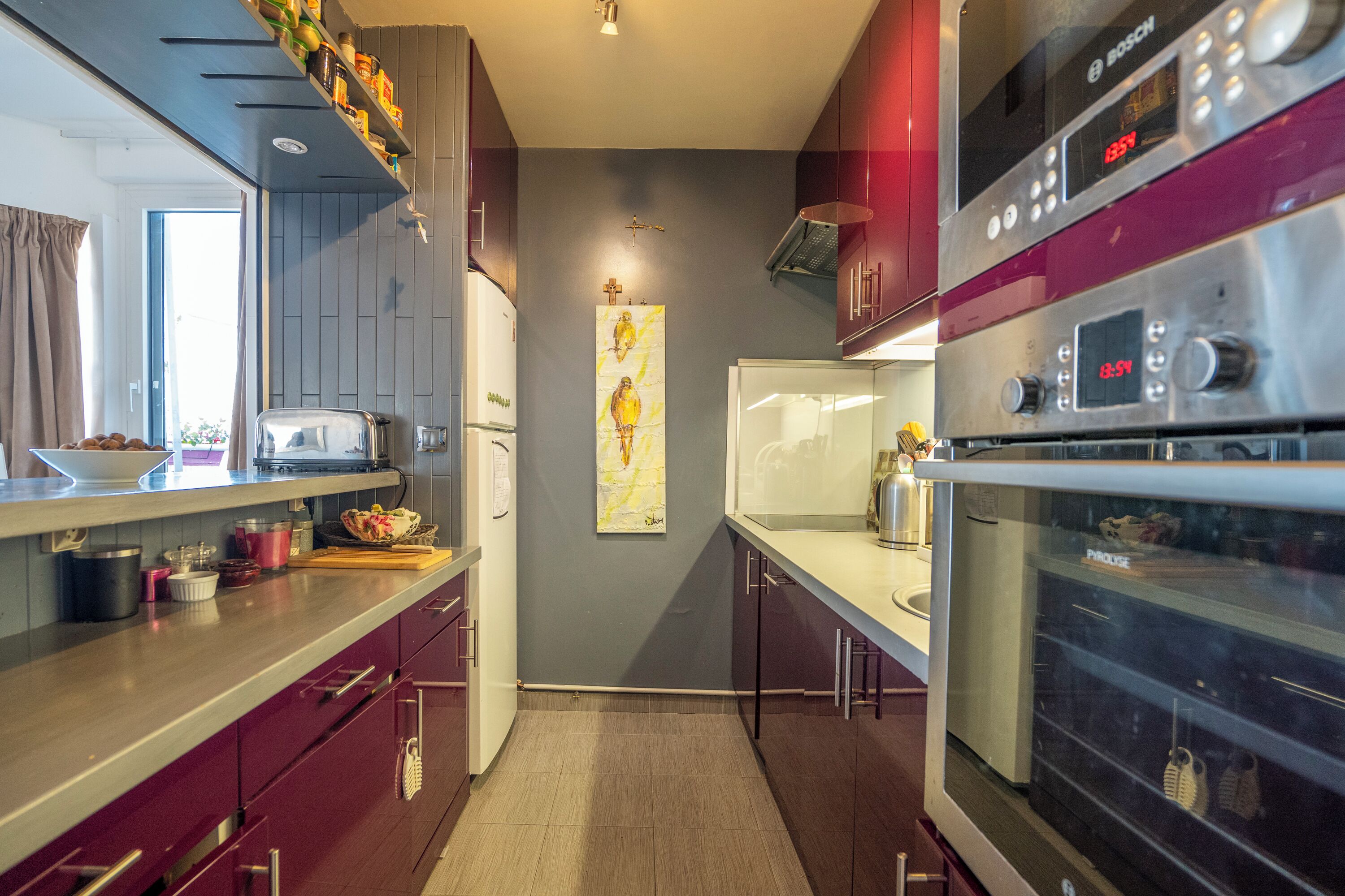 A modern kitchen with stainless steel appliances, a central island, and a decorative wall piece.