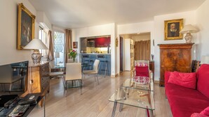 A modern living room with a glass coffee table, a red sofa, and a dining area with a glass table. - Panoramic Views from the 17th, by Veeve (Paris)