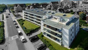 Ein mehrgeschossiges Wohngebäude mit Flachdach, Balkonen und Parkplätzen.