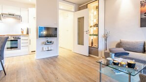 Ein modernes Wohnzimmer mit einem Glastisch, einem grauen Sofa und einem Fernseher.