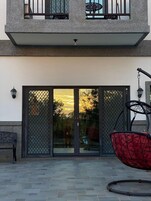 A two-story building with a balcony, a hanging chair, and a large sliding glass door.