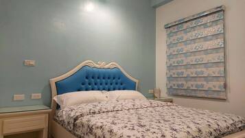 Une chambre à coucher comprenant un lit, des tables de chevet, une fenêtre avec des stores et un luminaire.