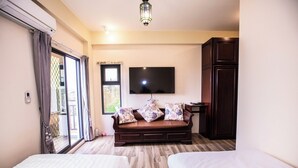 A hotel room with a sofa bed, two single beds, a TV mounted on the wall, and a wardrobe. - Chumentata (Jinsha)