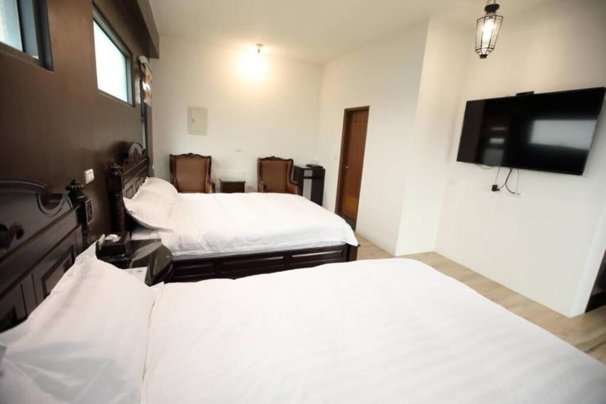 A hotel room with two beds, a TV, a desk, and a chair.