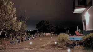A nighttime outdoor area with a pathway leading to a building. There are lights along the path, a pool, and some vegetation. - Chumentata (Jinsha)