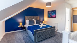 A bedroom with a sloped ceiling, a tufted bed, a radiator, and a painting on the wall. - Durham Deluxe Apartment With Stunning Views (Durham)