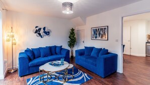 A modern living room with two blue sofas, a round coffee table, and a floor lamp. - Durham Deluxe Apartment With Stunning Views (Durham)