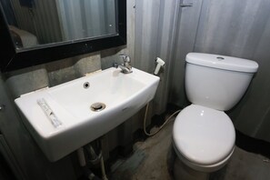 Une salle de bain avec un lavabo blanc, un miroir et des toilettes.